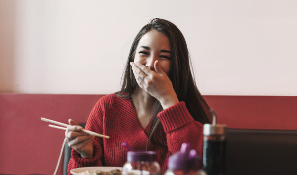Femme qui mange avec des baguettes dans un restaurant asiatique