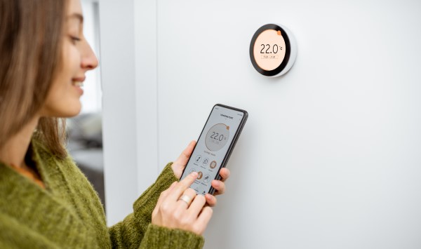 Woman adjusting the thermostat via her smartphone