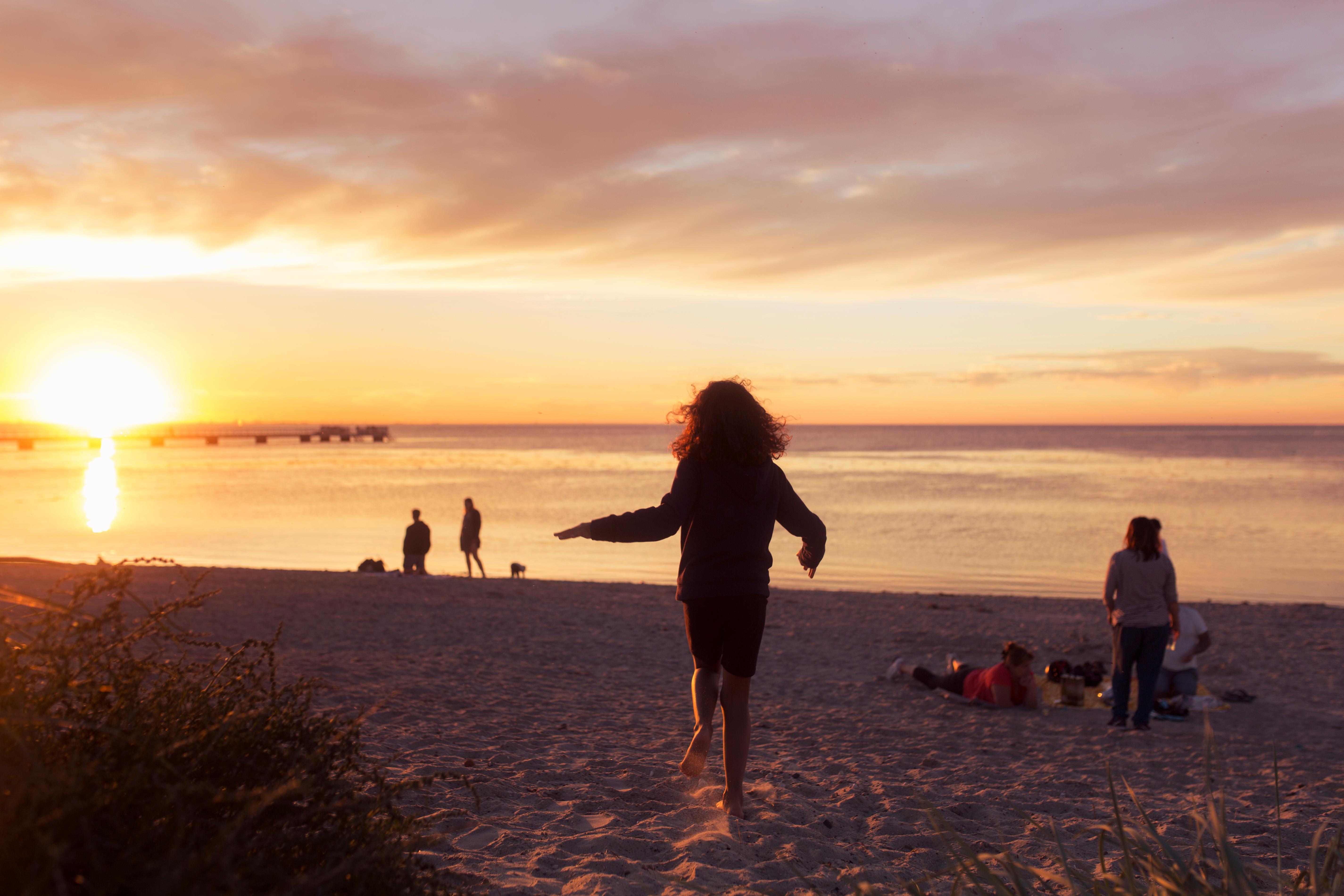 Jeune fille courant sur la plage au coucher de soleil
