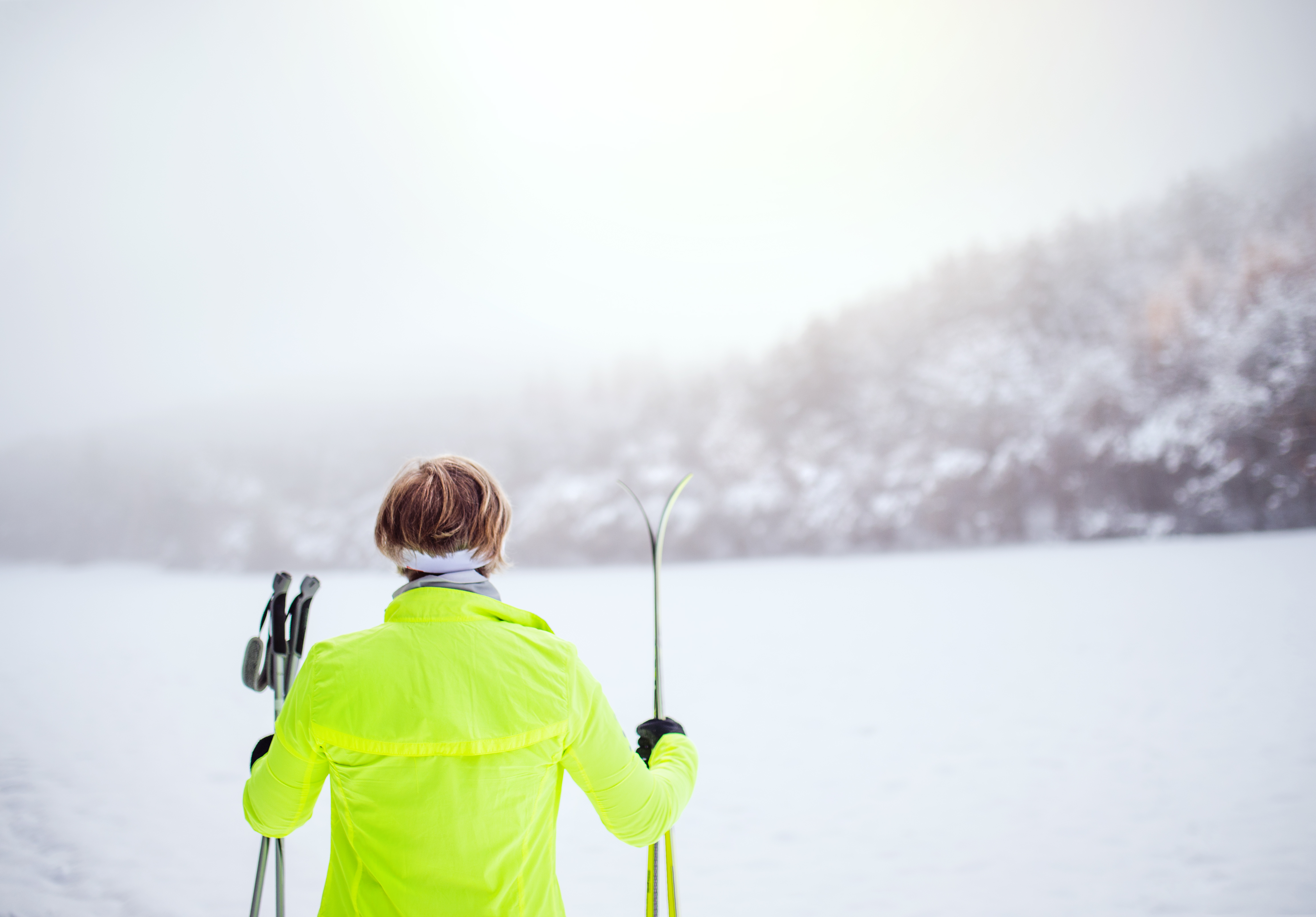 Femme en ski de fond devant un lac enneigé