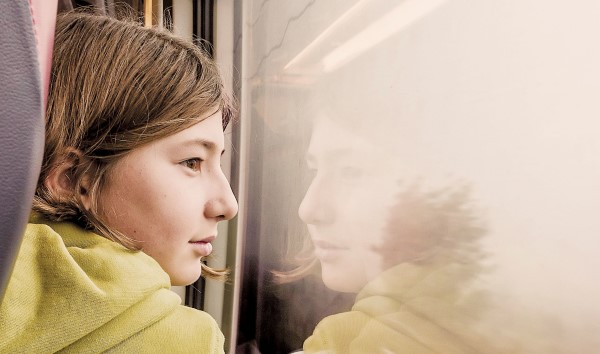 image d'un enfant qui regarde l'extérieur à travers la vitre d'un train
