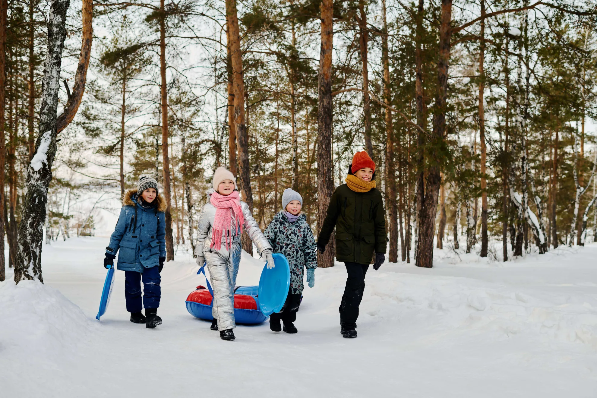 Quatre enfants avec des tubes à neige et des toboggans