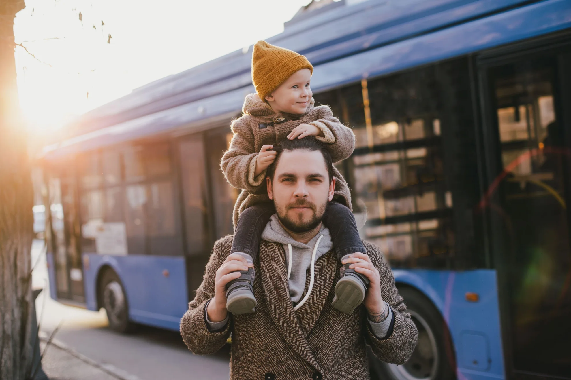 Papa avec son fils sur les épaules devant un autobus
