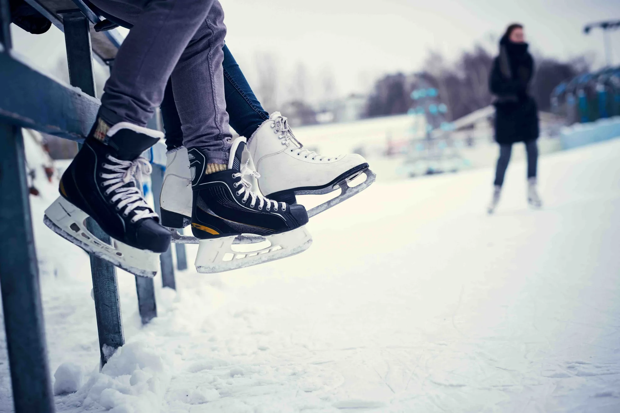 Patineur et patineuse qui enfilent leurs patins.